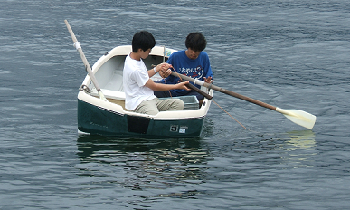 写真：ボートに乗り刺し網を回収している生徒(手前)