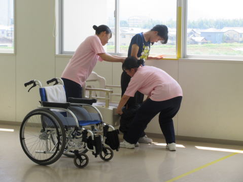 車椅子を使った実習を行う生徒の画像