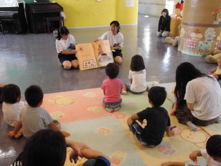 絵本の読み聞かせをして児童を楽しませている生徒の画像