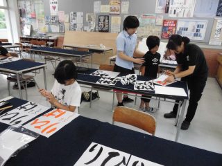 小学生に書道を教えている生徒の画像