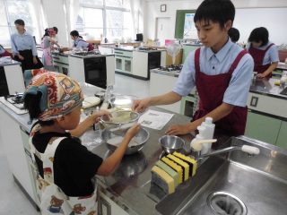 小学生に調理を教えている生徒の画像